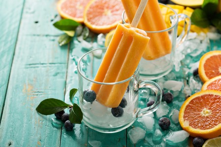 Mango banana popsicles on ice with fresh fruits and berries