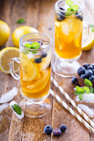 Iced tea with blueberries, lemon slices and mint on rustic backgroundの写真素材