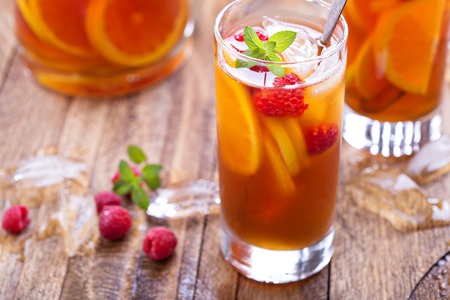 Iced tea with orange and raspberry in tall glasses on rustic backgroundの写真素材