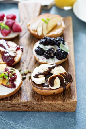 Variety of bagels with different toppings for breakfast on a boardの写真素材