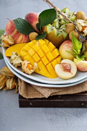 Assorted fresh ripe tropical fruits on a plate including mango, longan, kiwi and gooseberriesの写真素材