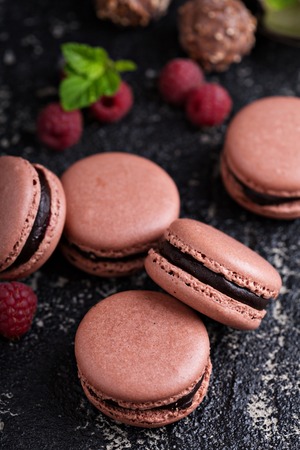 Chocolate and raspberry french macarons with ganache filling on a black tableの写真素材