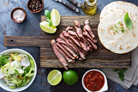 Cooking steak tacos with sliced meet and tortillas on a cutting boardの写真素材