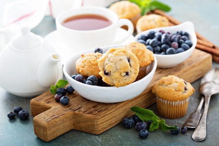 Blueberry muffins in a bowl with a cup of tea for breakfastの写真素材