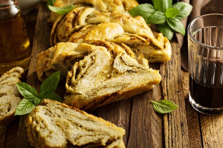 Homemade braided basil pesto bread sliced on a cutting board