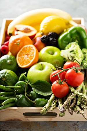 Fresh and colorful vegetables and fruits in a wooden crateの写真素材