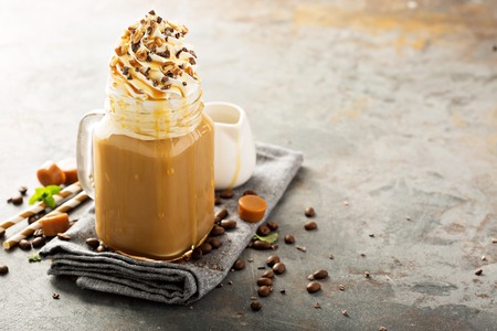 Caramel iced latte with whipped cream and syrup on light backgroundの写真素材