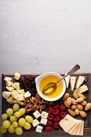 Cheese plate with nuts, honey, raspberry and grapesの写真素材