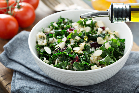 Warm kale salad with brown rice, almonds and dried cranberry with olive oil pouring overの写真素材