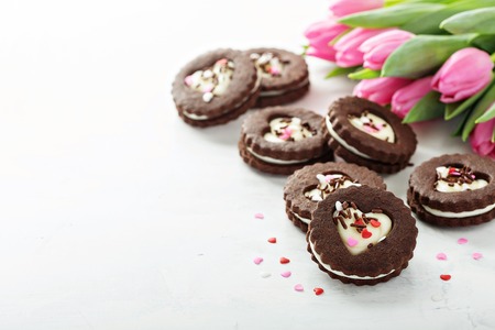 Chocolate cookie sandwiches with cream cheese filling for Valentines Day on white backgroundの写真素材