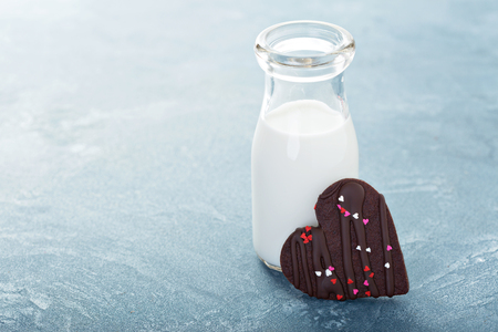 Chocolate hearts cookie with sprinkles for Valentines Day with a bottle of milkの写真素材