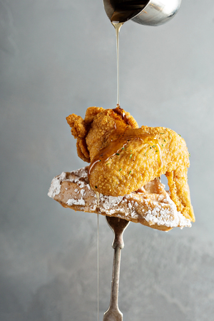 Fried chicken wing with a waffle on a fork with syrup pouring over, southern food conceptの写真素材