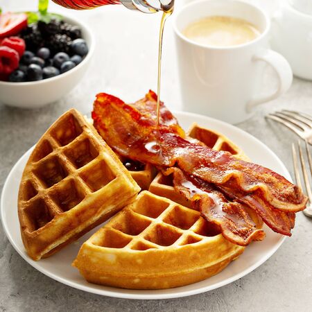 Breakfast plate with waffles and bacon, berries and maple syrupの写真素材