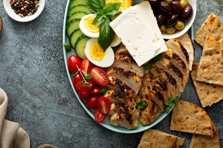 Grilled chicken platter with vegetables, grilled corn, eggs and feta cheese, greek inspired lunchの写真素材