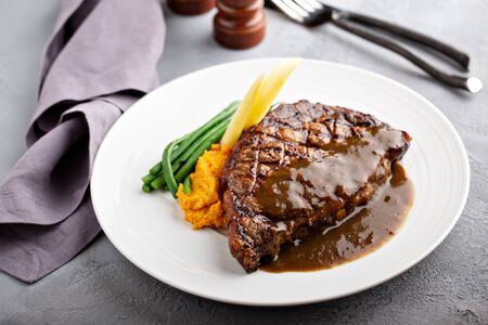 Grilled beef steak with gravy and vegetablesの写真素材