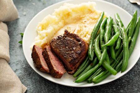 Traditional dinner meal with a bacon wrapped steak, green beans and mashed potatoesの写真素材