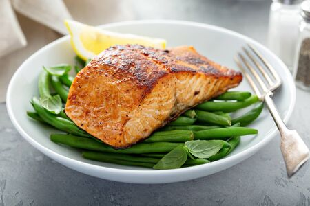 Grilled blackened salmon served with green beans and lemonの写真素材