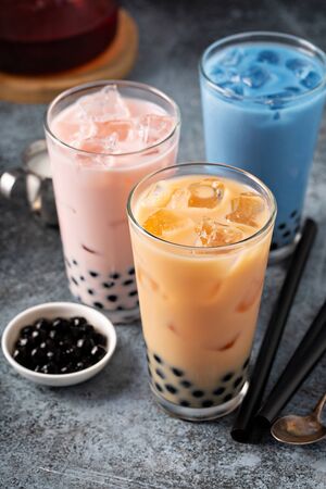 Variety of milk bubble tea in tall glasses, strawberry, butterfly tea and blackの写真素材