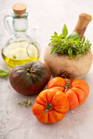 Ripe and fresh heirloom tomatoes with olive oil and herbsの写真素材
