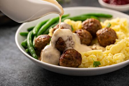 Swedish meatballs with mashed potatoes and green beans with gravy pouring overの写真素材