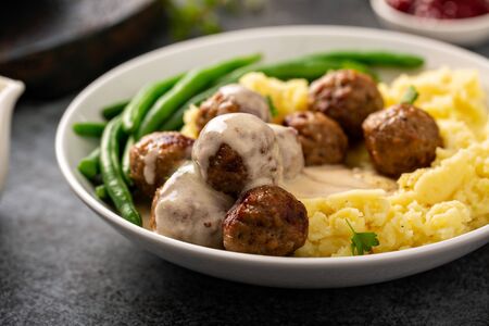 Swedish meatballs with mashed potatoes and green beans with gravy pouring overの写真素材