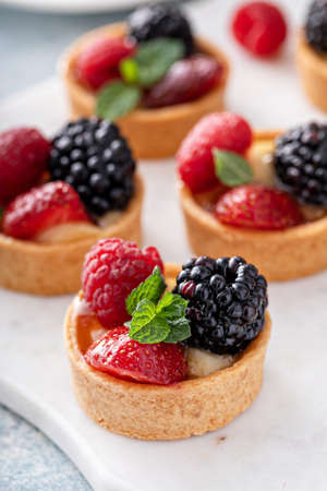 Fresh berries tartlets with custard filling and mint