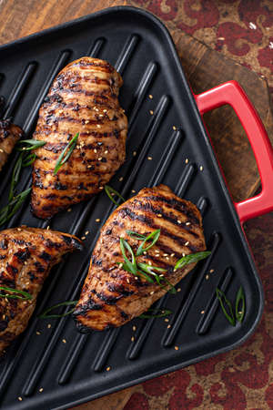 Grilled teriyaki chicken breast on a grill pan with green onions