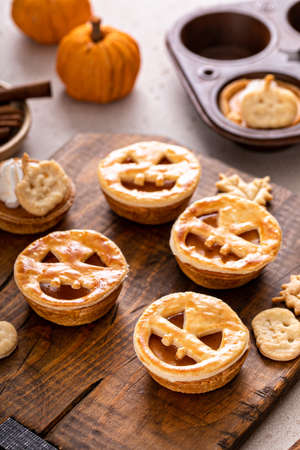 Halloween pumpkin pies with carved pumpkin face on topの写真素材