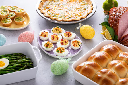 Easter brunch table with ham, quiche, hot cross buns and deviled eggsの写真素材