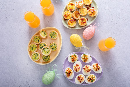 Deviled eggs and mini quiches, appetizers for Easter brunch with mimosa cocktailsの写真素材