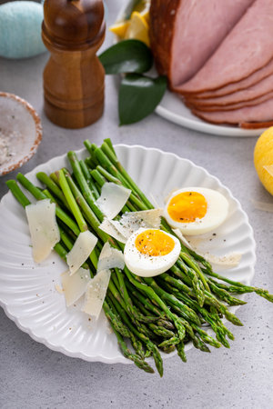 Asparagus cooked on a plate topped with parmesan cheese and soft boiled eggの写真素材