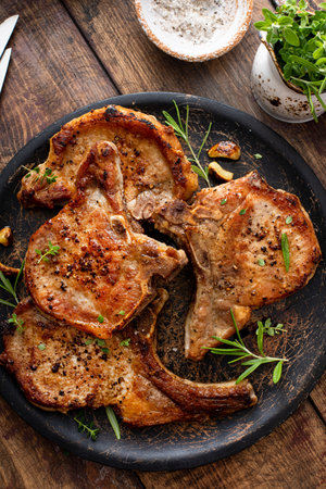 Pork chops grilled or seared with garlic and herbs bone in on a serving plateの写真素材