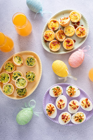 Deviled eggs and mini quiches, appetizers for Easter brunch with mimosa cocktailsの写真素材
