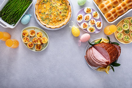 Easter brunch table with ham, quiche, hot cross buns and deviled eggs and mimosas top view with copy spaceの写真素材