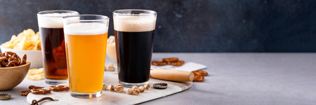 Variety of beer with dark stout, traditional lager and belgian white served with snacks on the table with copy spaceの写真素材