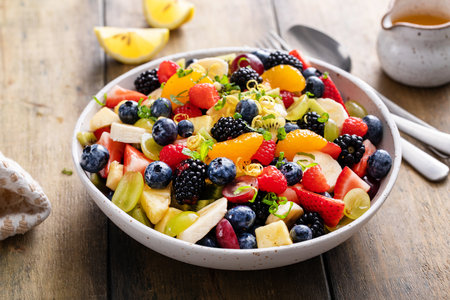 Fruit salad on a wooden table with berries and honey dressingの写真素材
