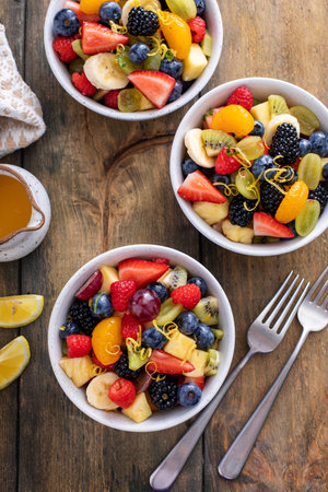 Fruit salad on a wooden table with berries and honey dressingの写真素材