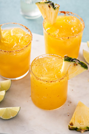 Pineapple margarita cocktail in glasses with tajin rimの写真素材