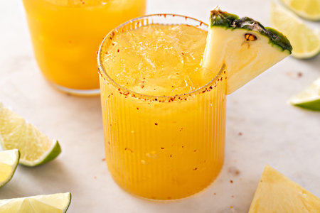 Pineapple margarita cocktail in glasses with tajin rimの写真素材