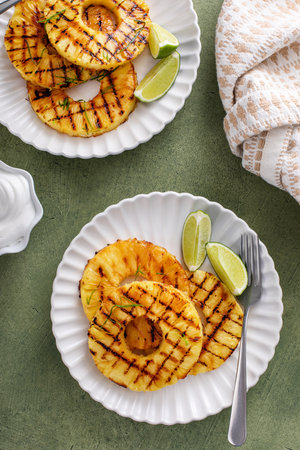 Grilled pineapple with lime honey glaze, lime zest and whipped cream overheadの写真素材