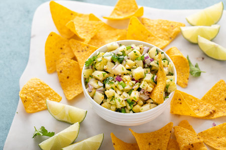 Fresh pineapple, red onion and jalapeno salsa in a bowl with tortilla chipsの写真素材