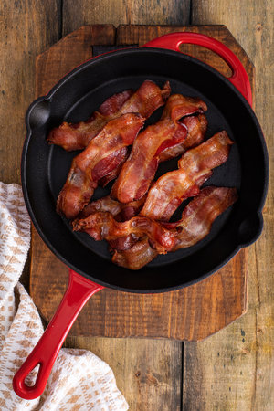 Cooked bacon in a cast iron pan, ready to eat breakfast stapleの写真素材