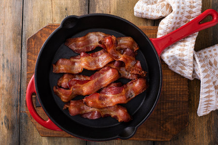 Cooked bacon in a cast iron pan, ready to eat breakfast stapleの写真素材