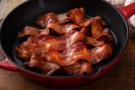 Cooked bacon in a cast iron pan, ready to eat breakfast staple