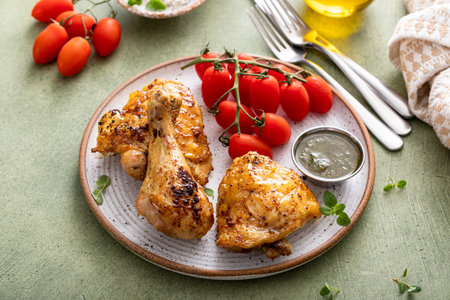 Roasted lemon and herb chicken drumsticks and thighs served with pesto sauceの写真素材