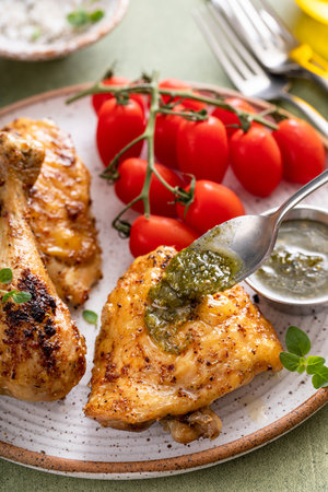 Roasted lemon and herb chicken drumsticks and thighs served with pesto sauceの写真素材