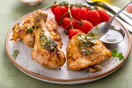 Roasted lemon and herb chicken drumsticks and thighs served with pesto sauceの写真素材