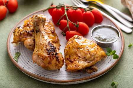 Roasted lemon and herb chicken drumsticks and thighs served with pesto sauceの写真素材