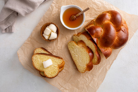 Freshly baked hallah sliced served with butter and honey, overhead shotの写真素材