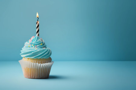 Birthday cupcake with a lit candle on a light blue background with copy space, generative AIの素材